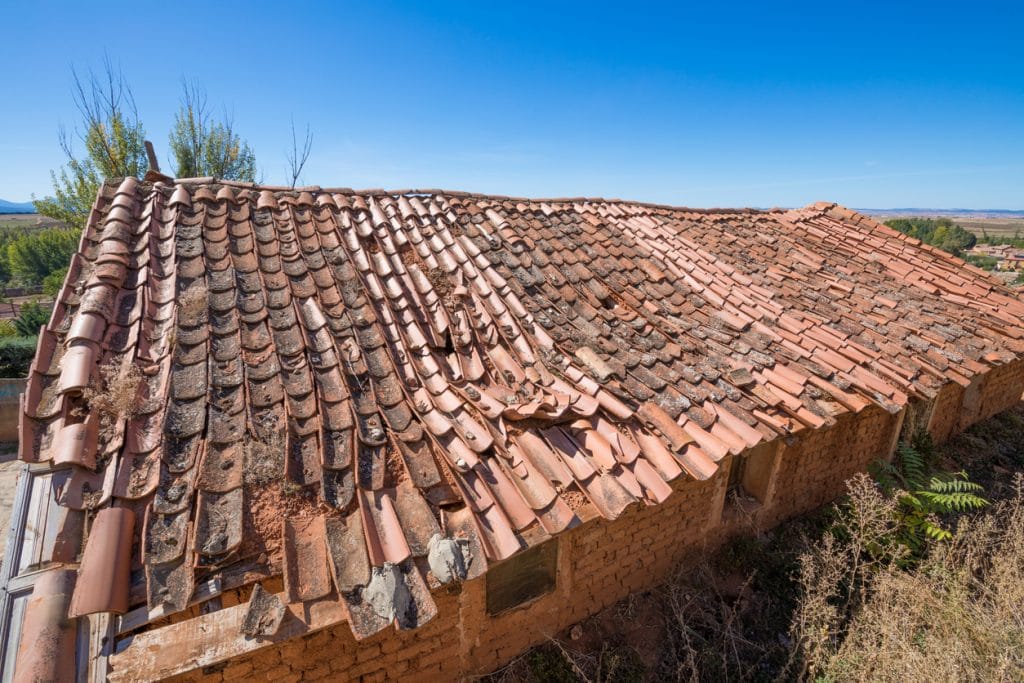 roof of building depressed with old clay tiles broken and blue sky