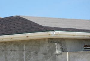 Roofing constraction. Install house roof gutter and laying asphalt shingles. Roof repair.